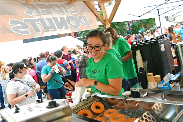 A cheerful volunteer preparing apple cider donuts!